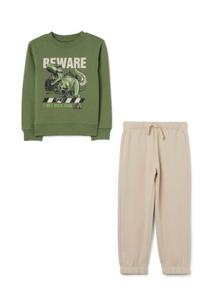 Green sweatshirt with dinosaur graphic and text, paired with beige sweatpants featuring an elastic waistband and cuffed ankles.