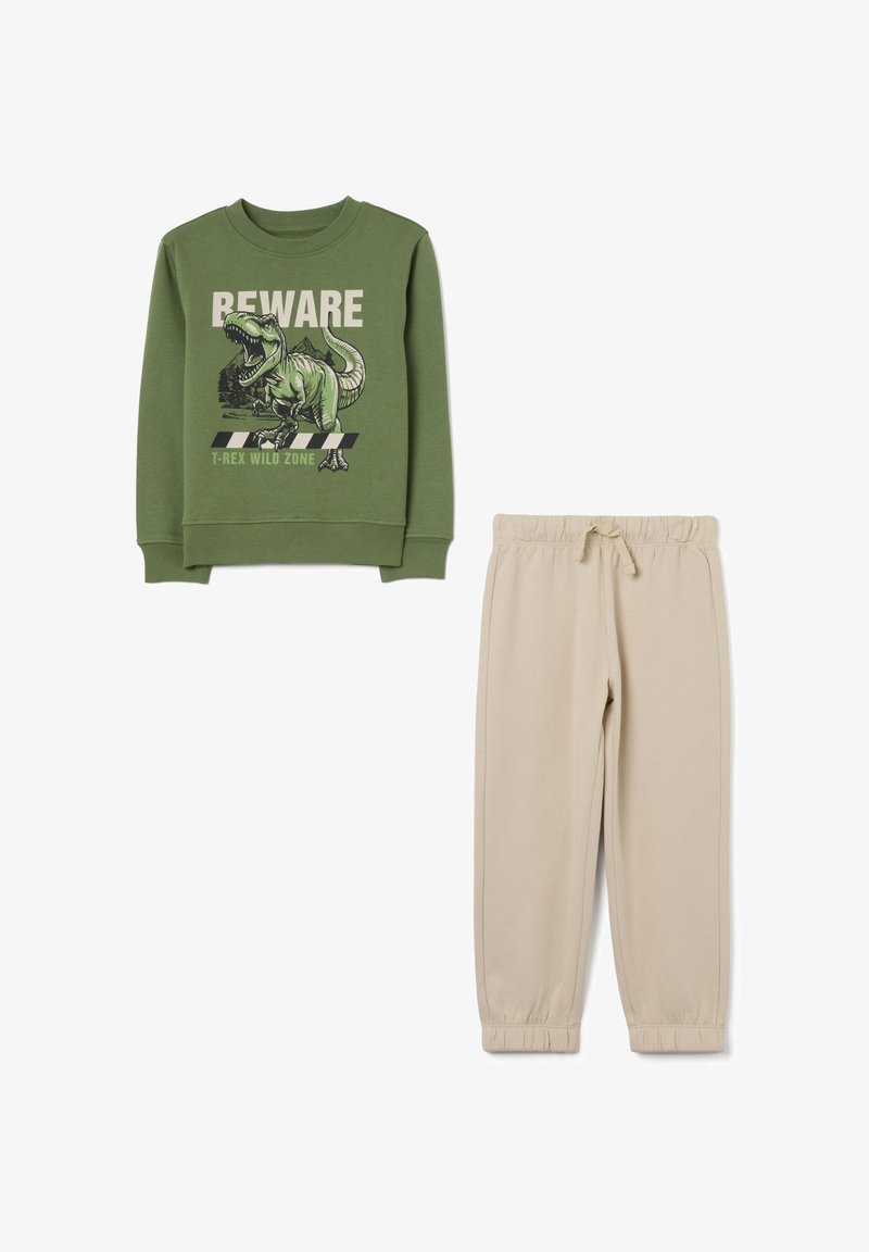 Groene sweatshirt met een dinosaurustekening en tekst, gecombineerd met beige sweatpants met een elastische tailleband en cuffed enkels.