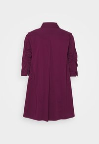Abito camicia color prugna con colletto alto, maniche a tre quarti e dettagli arricciati ai polsi. Il design della schiena plissettata aggiunge struttura.