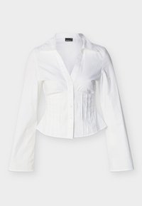 Λευκό εφαρμοστό πουκάμισο με μακριά μανίκια, γιακά, κουμπιά στο μπροστινό μέρος και κάθετες πιέτες στη δεξιά πλευρά.