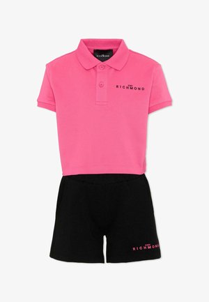 Polo rosa corta con pantaloncini neri, entrambi con il logo "John Richmond" in colori contrastanti.