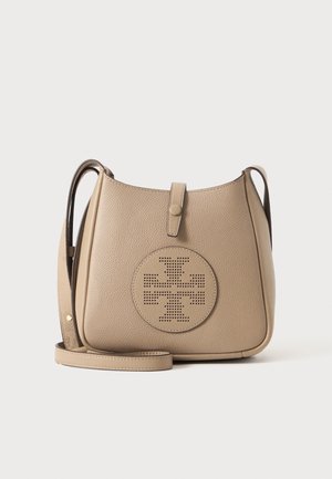 Sac bandoulière en cuir beige avec sangle réglable et détail de logo circulaire perforé à l’avant sur un fond uni.