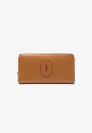 Portefeuille rectangulaire en cuir marron clair avec des bords arrondis et une pièce ovale cousue présentant un logo en relief au centre.