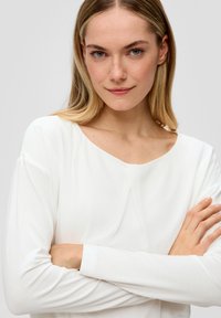 Witte lange mouwen top met een ronde halslijn en draperende voorkant, gemaakt van zachte stof, heeft fitted mouwen en een ontspannen silhouet.