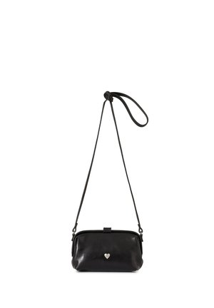 Bolso bandolera de cuero negro con correa larga y pequeño emblema de corazón plateado centrado delante.