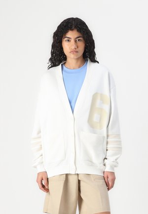 Cream cardigan with a V-neck, five buttons, and a large beige number '6' on the front. Features two front pockets and striped sleeve details.
