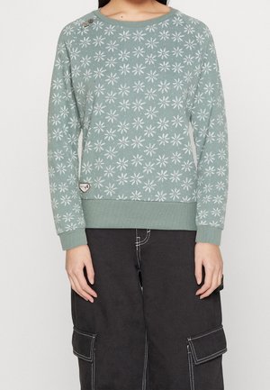 Lichtgroene trui met een wit bloemenpatroon. Geribbelde manchetten en zoom. Twee knopen op de schouder. Zachte, gestructureerde stof.