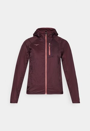 Veste légère bordeaux avec capuche, devant zippé et accent de poche rose. Présente une texture lisse et un design ajusté.