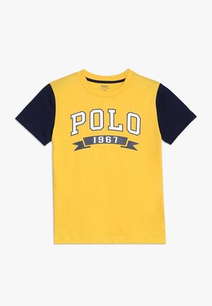 Gelbes Baumwoll-T-Shirt mit marineblauen Ärmeln, das auf der Vorderseite "POLO" und "1967" in kontrastierenden Buchstaben aufgedruckt hat. Runder Ausschnitt.