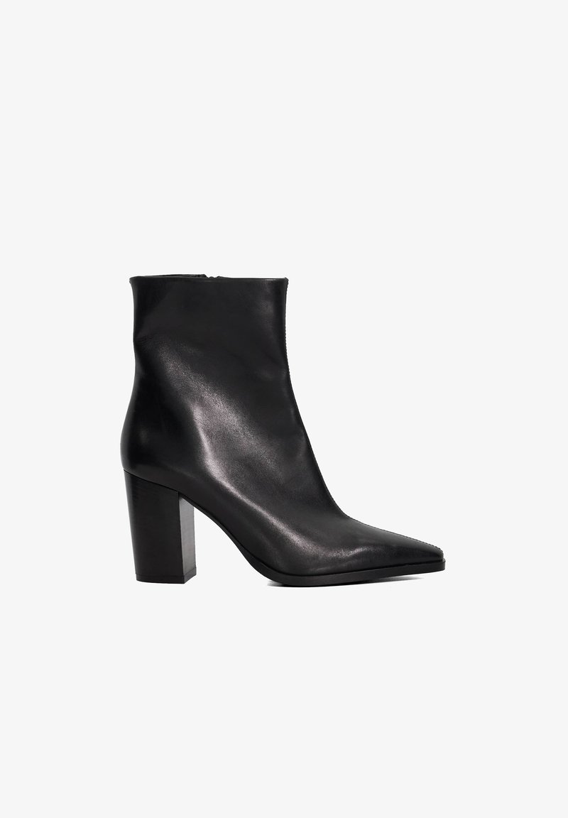 Bottine en cuir noir avec un bout pointu, texture lisse et un talon carré. Présente un design propre et minimaliste.