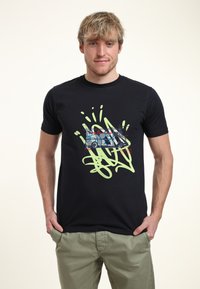 Camiseta de algodón negra con un diseño gráfico colorido que incluye elementos de graffiti y una ilustración de un camión, acentuada con detalles en verde claro.