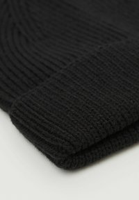 Beanie noir en tricot avec une texture côtelée, dotée d'un revers replié pour plus de chaleur et un ajustement confortable. Matériau doux et épais.