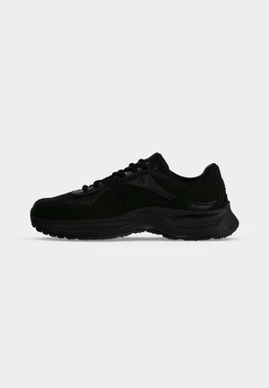 Sort lavt sneakers med snørelukning, tekstureret sål og diskret branding på siden, vist fra ydersiden mod en ensfarvet baggrund.