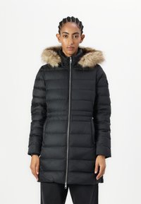 Crni zimski kaput s perjem i odvojivom umjetnom krznom na kapuljači, prednjim zatvaračem i osjećajem prekrivene teksture. Dugi rukavi i podesiv struk.
