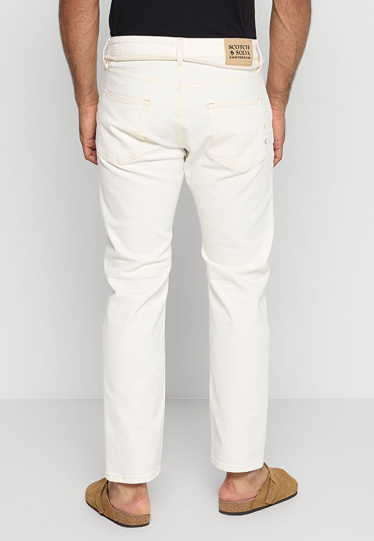 Jeans de mezclilla blanca con corte recto, que cuentan con bolsillos traseros, un parche de piel con la marca y detalles de costura en contraste. Textura suave.