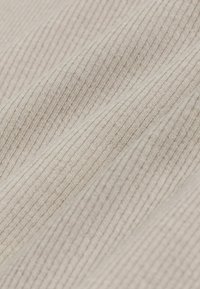 Tessuto beige chiaro con un motivo a coste testurizzato, caratterizzato da linee sottili e leggere variazioni di colore. Texture morbida e liscia.