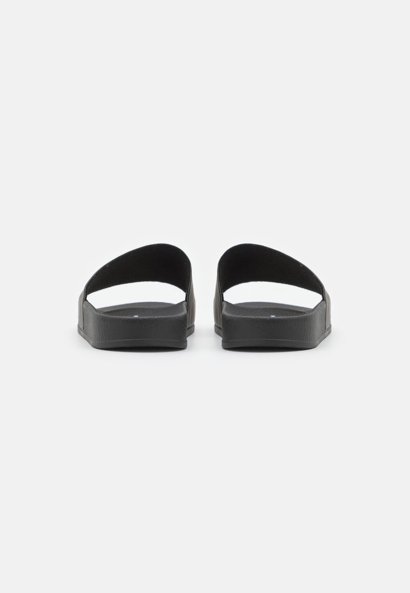 Schwarze Riemchensandalen mit minimalistischem Design, weichem Gummi-Material, offenen Zehen und rückenfreiem Stil sowie flacher, strukturierter Sohle.