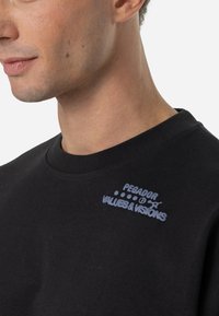 Black cotton sweatshirt featuring a curved neckline, ribbed cuffs, and light blue text logo on the upper left chest.