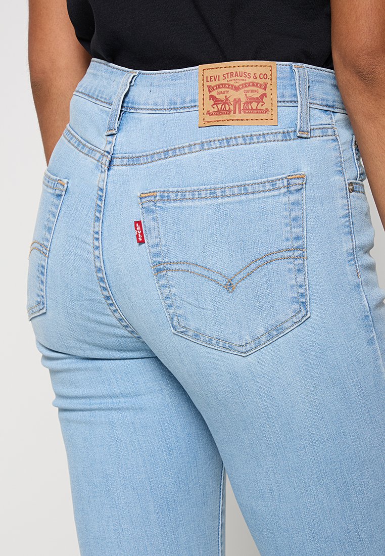 Hellblaue Denim-Jeans mit hoher Taille. Verfügt über ein tanfarbenes Lederetikett mit geprägtem Logo und zwei hinteren Taschen mit markanten Nähten.