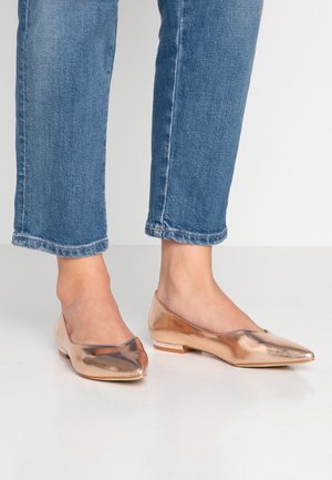 Rosaguld flade sko med spids tå-design, skinnende metalfinish og en lav hæl. Båret med cropped blå jeans.