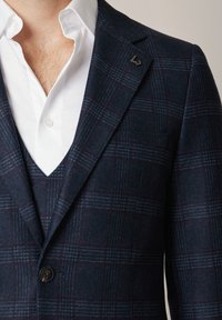 Granatowa marynarka w kratę z teksturowanej wełny, charakteryzująca się dopasowanym krojem, wykładanymi klapami oraz subtelnymi wzorami w bordowym i niebieskim odcieniu.
