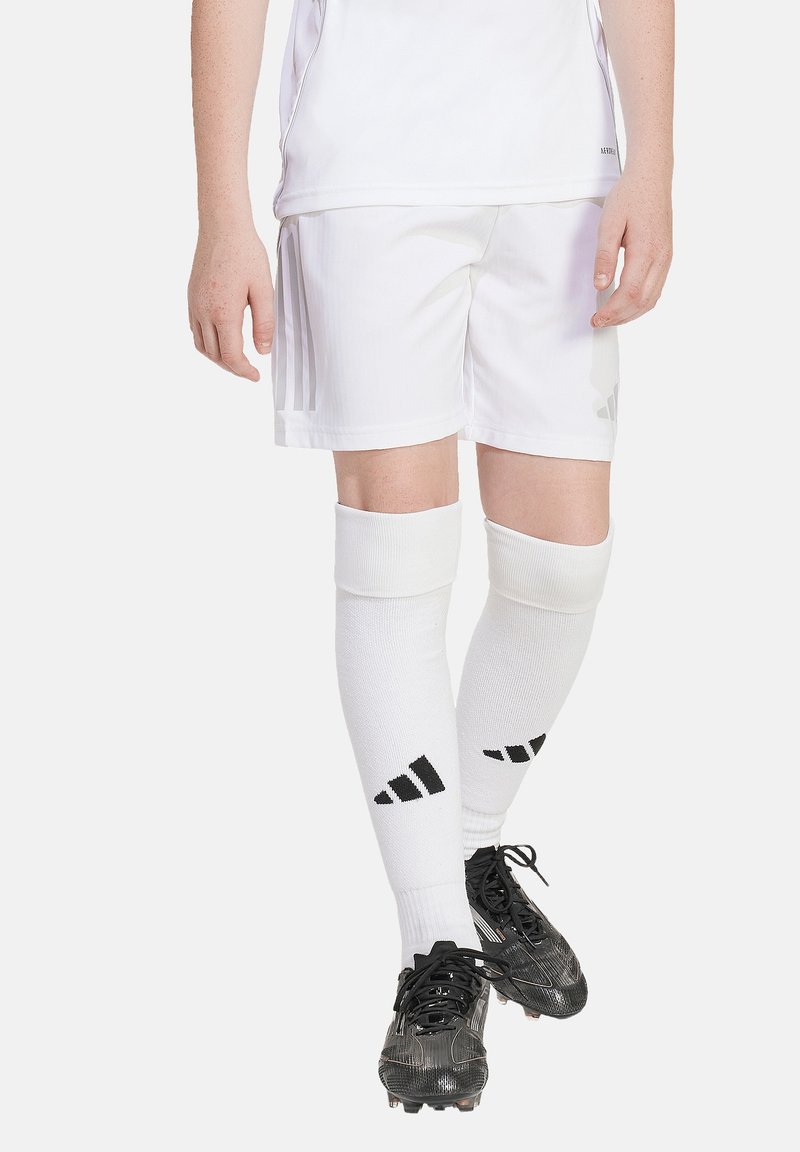 Weiße Fußballshorts mit vertikalen hellgrauen Streifen, kombiniert mit knielangen weißen Socken mit schwarzen adidas-Akzenten und schwarzen Fußballschuhen.