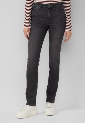 Jeans neri slim con due tasche frontali, zip e leggeri segni di sbiadimento. Abbinati a scarpe da ginnastica bianche per un look informale.