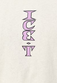 Krémové bavlněné tričko s vertikálním černým a levandulovým textem, na kterém je napsáno "ICE•T." Jednoduchý design s měkkou texturou.