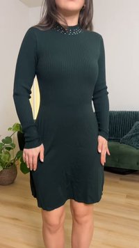 Térd alá érő, sötétzöld bordázott ruha hosszú ujjakkal és díszített nyakkivágással. Puha anyagból készült, testhezálló felsőrésszel és bővülő szegéllyel.
