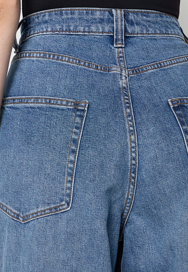 Jean en denim bleu clair avec une taille haute. Comprend de grandes poches arrière, des coutures verticales et des accents de couture subtils.