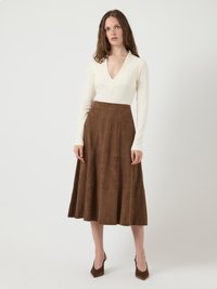 Atasan lengan panjang krem dengan leher V yang dalam, dipasangkan dengan rok A-line suede cokelat. Paduan ini dilengkapi dengan sepatu hak tinggi cokelat.