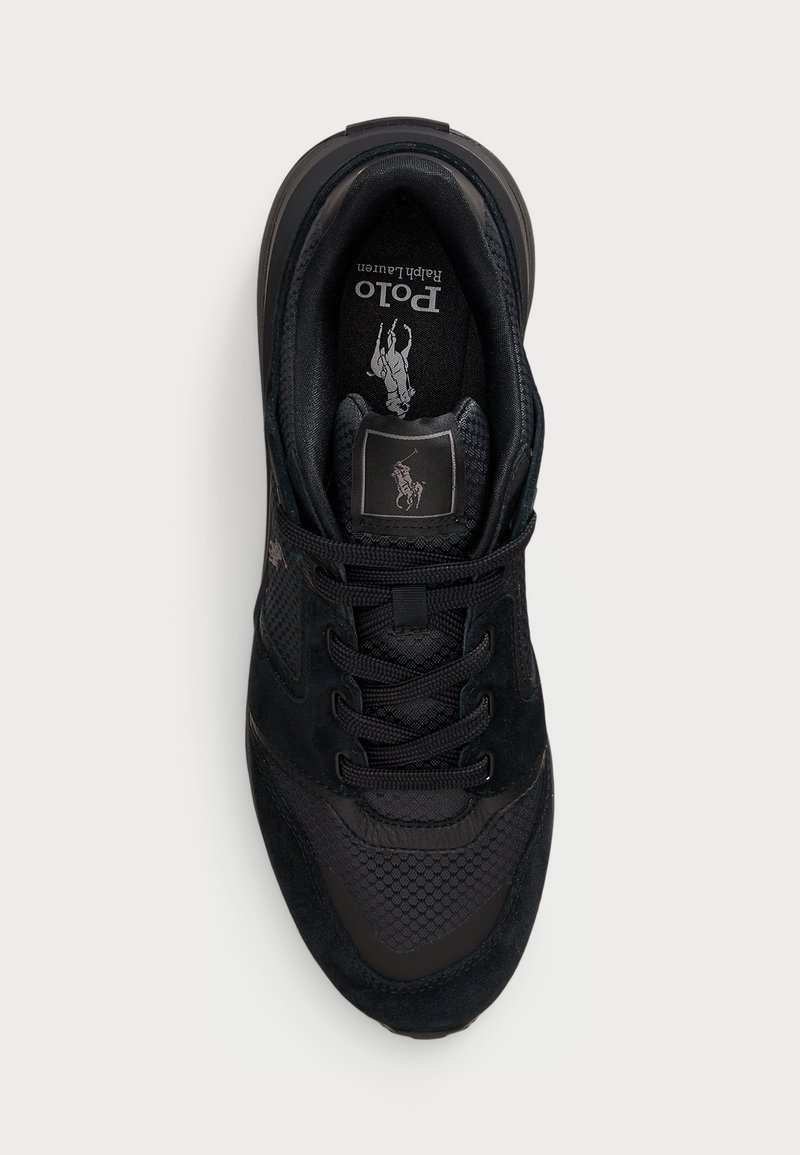 Schwarze Sneaker aus einer Mischung aus Wildleder und Mesh-Materialien, mit runden Schnürsenkeln, gepolstertem Schaft und einem Logopatch auf der Zunge. Strukturiertes Profil.