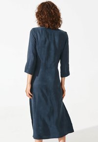 Marineblaue Midikleid aus weichem Stoff, mit Dreiviertelärmeln und einer einfachen, geraden Silhouette mit glatter Textur.