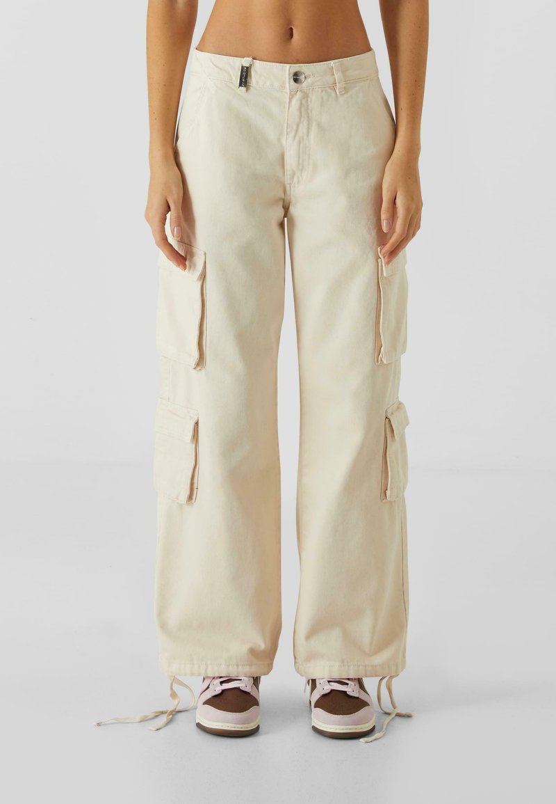 Beige cargo bukser med brede ben, lavet af denim, med to sidelommer, justerbare linninger og lynlås lukning.