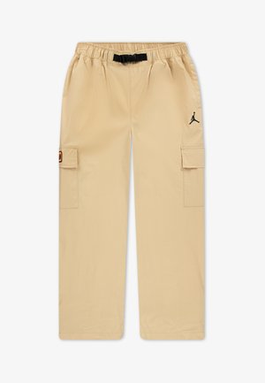 Beige cargo nadrág elasztikus derékrésszel és fekete húzózsinórral, oldalán cargo zsebekkel és fekete logóval a bal combján.