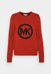 Czerwona wełniana bluza z czarnym okrągłym logo z napisem "MK" na środku. Prążkowane mankiety i dół nadają teksturowane wykończenie.