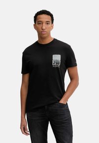 Camiseta de algodón negra con un gráfico de un bolsillo en la parte frontal que representa la ciudad de Nueva York con un diseño gris y texto blanco; corte estándar con mangas cortas.