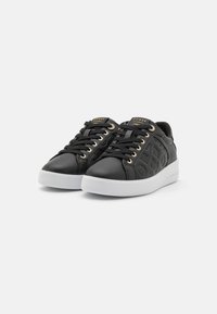 Svarta lädersneakers med präglade logotypmönster, gyllene ögla, svarta snören och vita gummisulor. Diskret varumärkesdetalj på tungan.