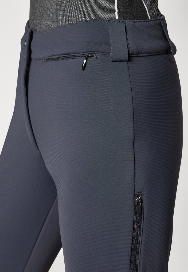 Pantaloni sportivi navy realizzati in tessuto testurizzato. Presentano una tasca anteriore con zip e una tasca laterale con zip per il deposito.