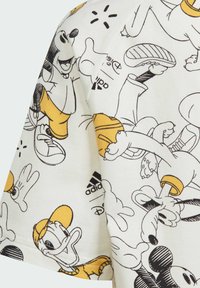 T-shirt bianca a maniche corte in cotone con una stampa giocosa di personaggi Disney in contorni neri e gialli, con il marchio Adidas.