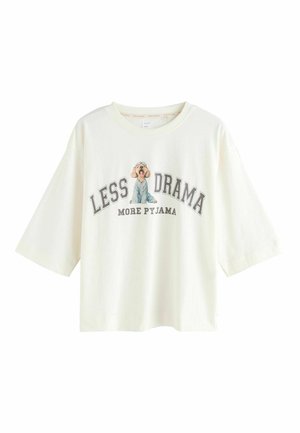 Fehér, rövidujjú pamut póló, kék pizsamában lévő kutya grafikájával és a "KEVÉS KÁOSZ TÖBB PIZSAMA" felirattal szürke színben.