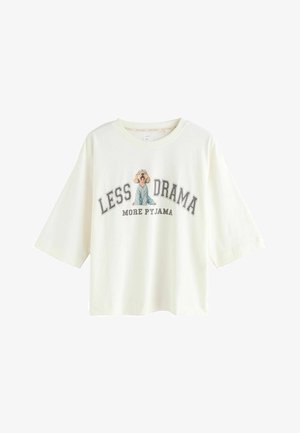 Fehér, rövidujjú pamut póló, kék pizsamában lévő kutya grafikájával és a "KEVÉS KÁOSZ TÖBB PIZSAMA" felirattal szürke színben.