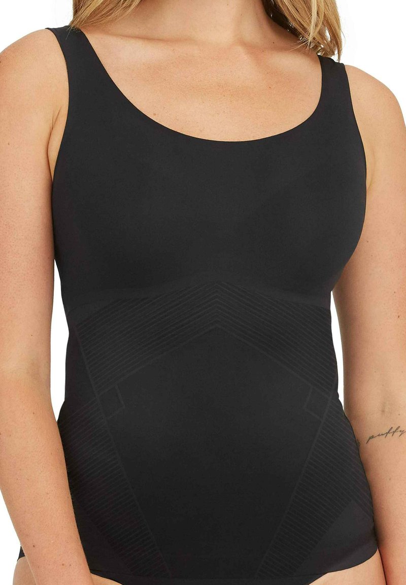 Débardeur noir avec un décolleté arrondi, fabriqué en tissu lisse. Présente un motif géométrique texturé dans une teinte légèrement plus foncée.
