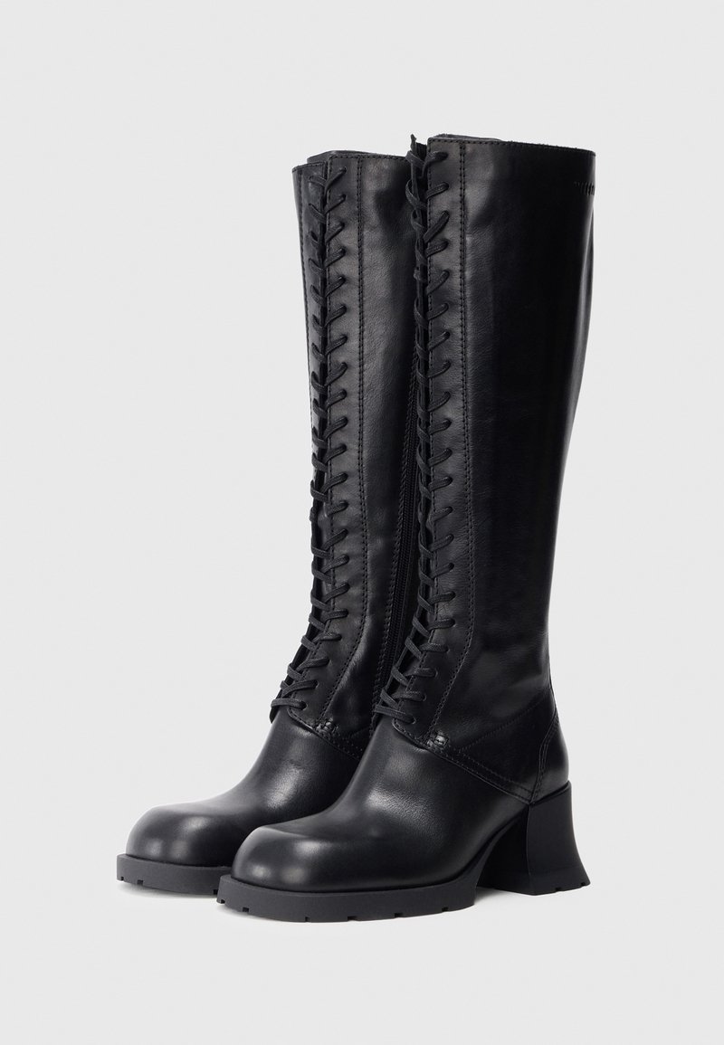 Knæhøje sorte læderstøvler med en glat tekstur, snørelukning foran og en chunky hæl. Har en sidelås for nem påtagning.