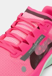 Baskets de trail de course Nike rose vif avec tige en maille, lacets assortis, logo swoosh noir et étiquette "Vaporweave" sur le côté.