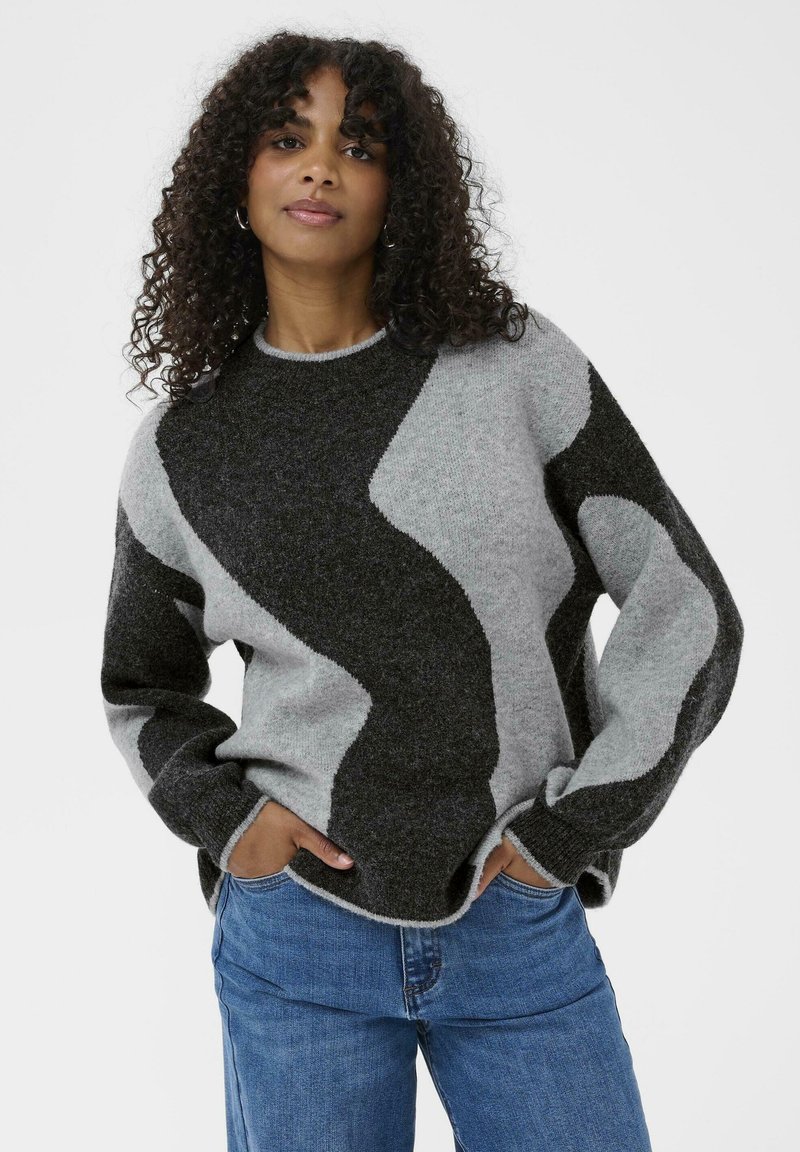 Knitted sweater featuring a wave pattern in gray and dark gray shades, rounded neckline, and cuffed sleeves. Worn with blue jeans.