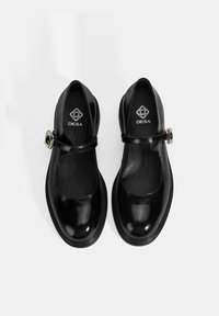 Schwarze Leder-Mary-Jane-Schuhe mit runder Spitze, Riemen und Schnallen-Detail, mit glänzender Oberfläche und flacher Sohle. Logo geprägt im Inneren.