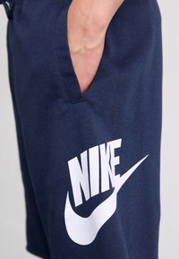 Námornícky modré šortky Nike vyrobené z mäkkej zmesi bavlny, s veľkým bielym logom na prednej strane a bočnými vreckami pre pohodlie.