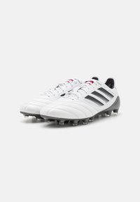 Weiße Fußballschuhe aus glattem Leder mit schwarzen gestreiften Akzenten. Sie verfügen über sechs schwarze geformte Stollen und rote Schnürsenkel.