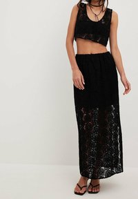 Sort blonde to-delt sæt med en kort top med rund halsudskæring og en lang nederdel med elastisk talje og gennemsigtigt blomsterprint.